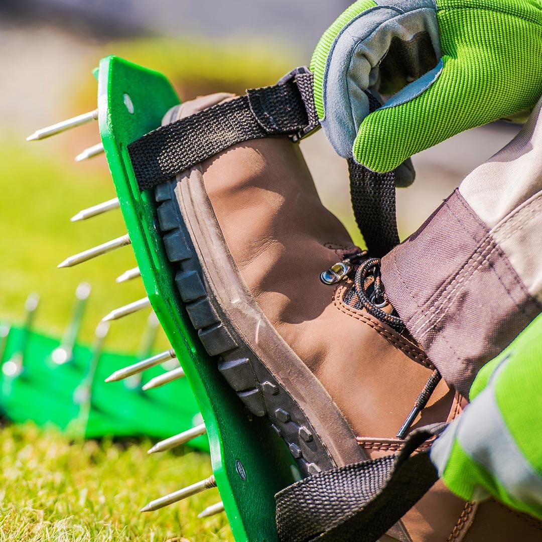 Worker wearing lawn aeration shoes